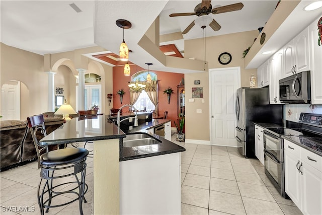 kitchen featuring white cabinets, appliances with stainless steel finishes, decorative columns, and hanging light fixtures