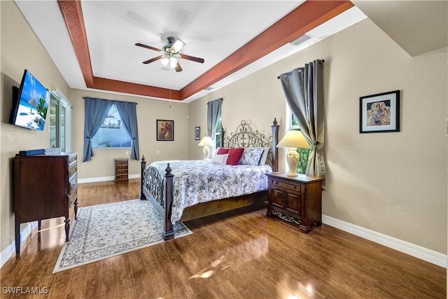 bedroom featuring ceiling fan, dark wood-type flooring, and a tray ceiling