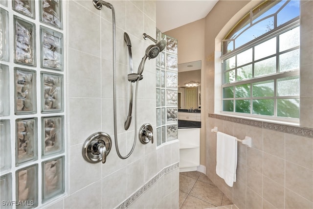 bathroom with a tile shower, tile patterned floors, and tile walls