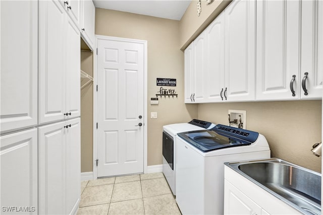 washroom with light tile patterned flooring, cabinets, sink, and washing machine and clothes dryer