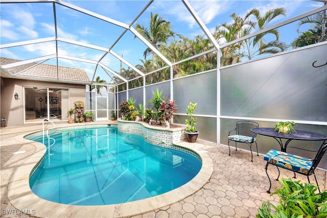 view of pool featuring glass enclosure and a patio area