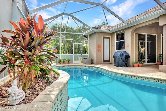 view of pool with glass enclosure and grilling area