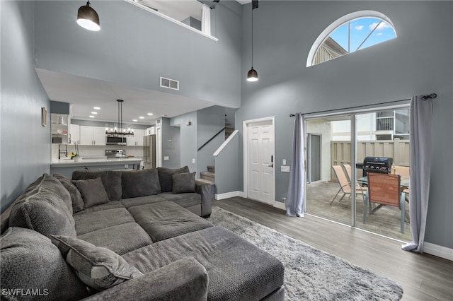 living room with stairs, visible vents, baseboards, and wood finished floors