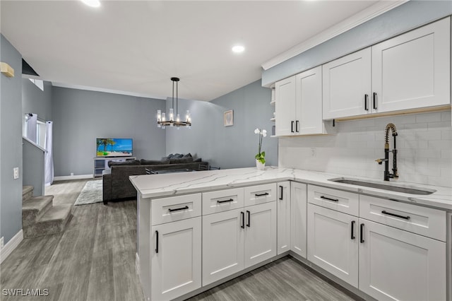 kitchen with kitchen peninsula, decorative backsplash, sink, light hardwood / wood-style flooring, and white cabinets