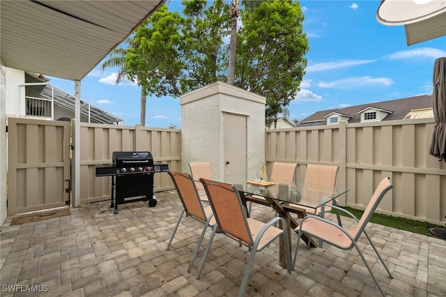 view of patio / terrace with a storage shed and a grill