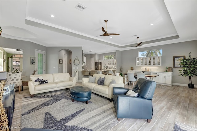 living room featuring ornamental molding, a tray ceiling, and light hardwood / wood-style flooring