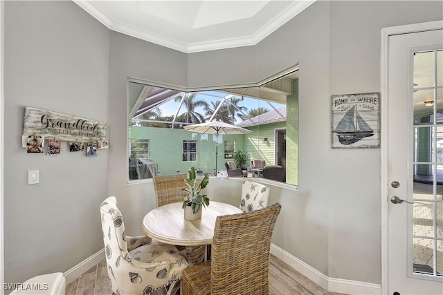 dining area with ornamental molding, light wood-type flooring, a sunroom, and baseboards