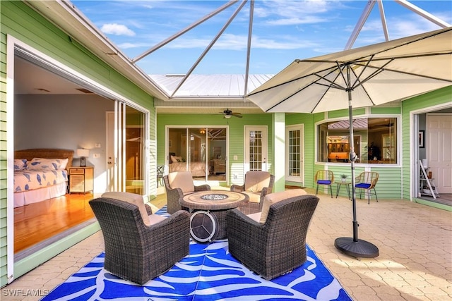 view of patio / terrace featuring ceiling fan, an outdoor living space with a fire pit, and a lanai