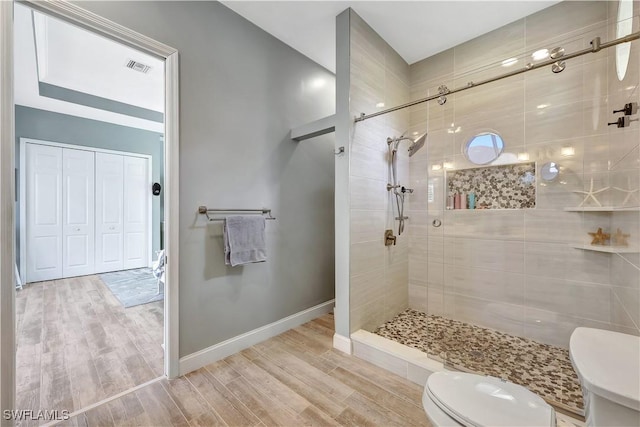 full bath featuring toilet, wood finished floors, visible vents, baseboards, and a stall shower