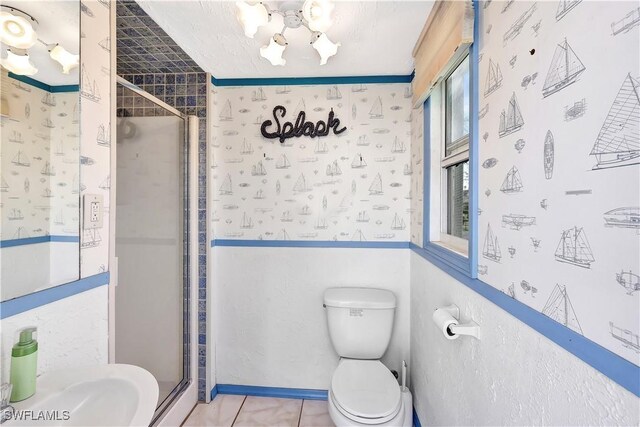 bathroom featuring tile patterned floors, a shower with shower door, and toilet