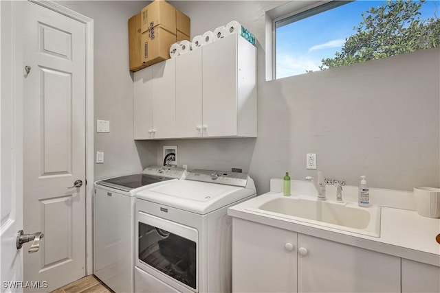 washroom featuring cabinet space, washer and clothes dryer, and a sink