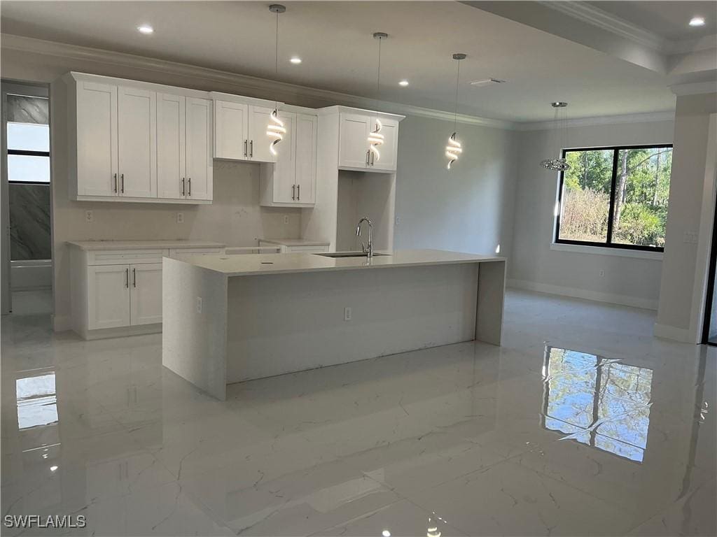 kitchen with pendant lighting, a center island with sink, and white cabinetry