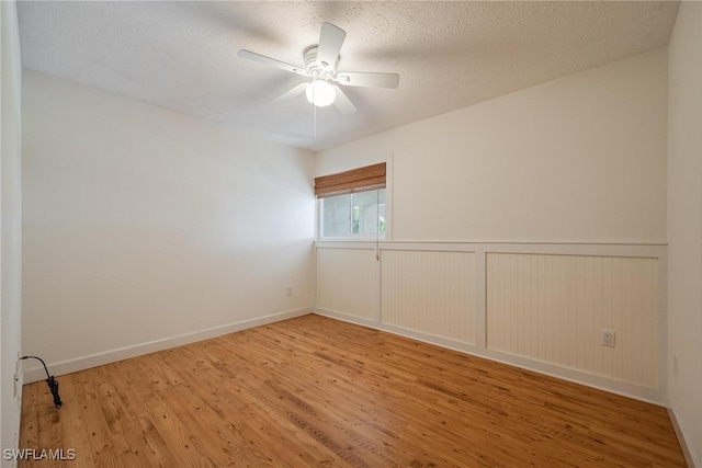 unfurnished room with ceiling fan, wood-type flooring, and a textured ceiling