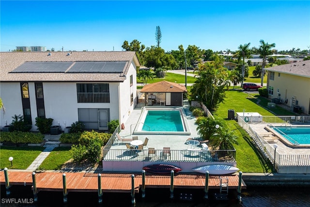 back of property with solar panels, a patio, and a fenced in pool