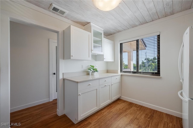 kitchen featuring white refrigerator, light wood-type flooring, white cabinetry, and wood ceiling