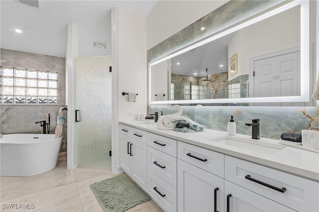 bathroom with plus walk in shower, vanity, tile patterned floors, and tile walls