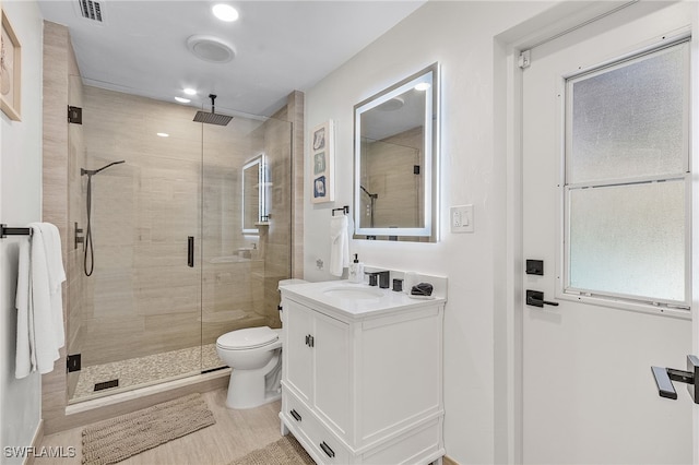 bathroom with a shower with door, vanity, and toilet