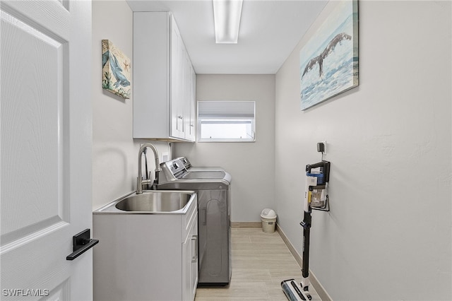 laundry room featuring washing machine and dryer, sink, and cabinets