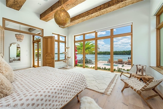 bedroom featuring access to exterior, a water view, beamed ceiling, baseboards, and hardwood / wood-style flooring