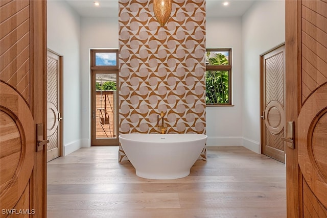 full bathroom with a freestanding bath, recessed lighting, wood finished floors, and baseboards