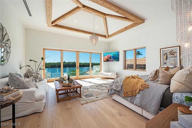 living room with hardwood / wood-style floors, a water view, a high ceiling, beam ceiling, and a notable chandelier