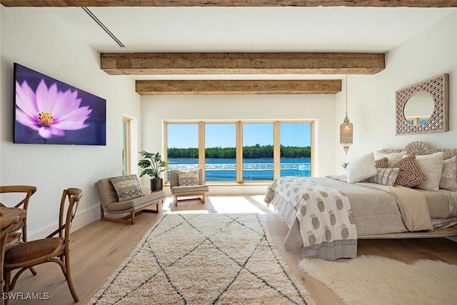 bedroom with baseboards, beamed ceiling, and wood finished floors