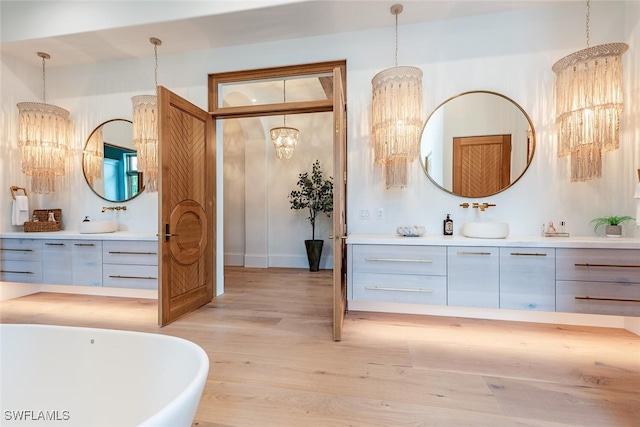 full bathroom featuring a soaking tub, wood finished floors, and vanity