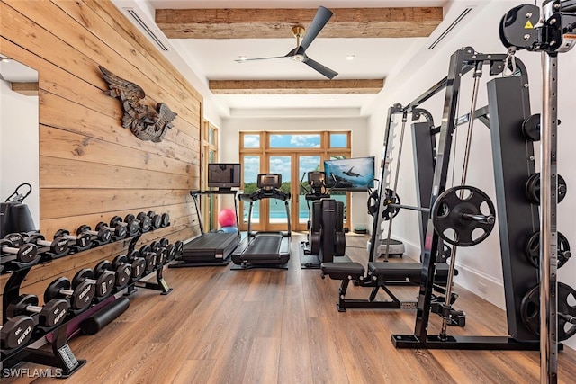 workout area featuring visible vents, ceiling fan, wooden walls, and wood finished floors