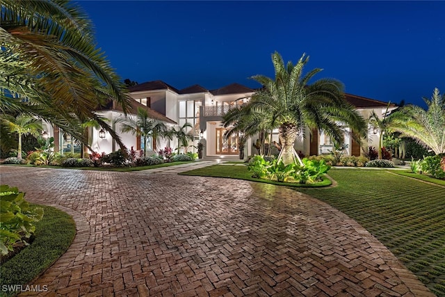 mediterranean / spanish home featuring stucco siding, decorative driveway, and a yard