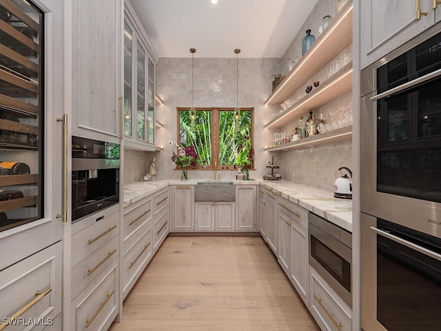 kitchen featuring open shelves, hanging light fixtures, glass insert cabinets, appliances with stainless steel finishes, and light stone countertops