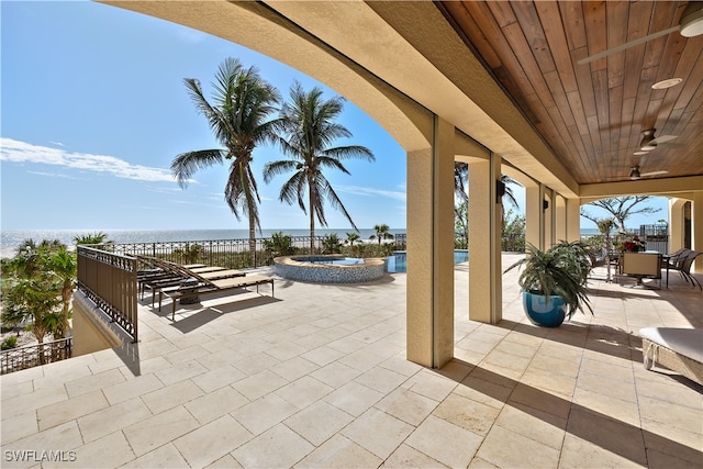 view of patio featuring a water view and an in ground hot tub