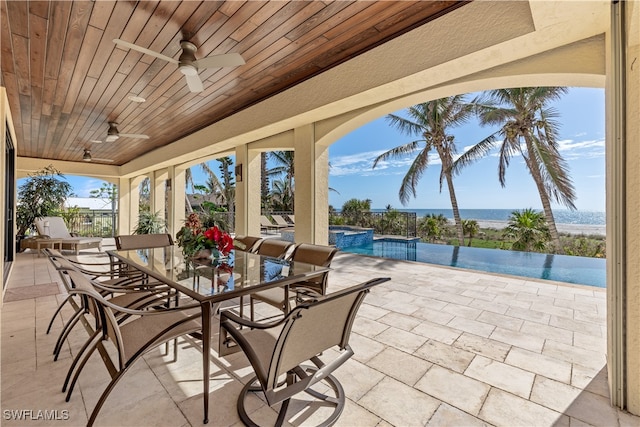 view of patio / terrace with a swimming pool with hot tub, a water view, and ceiling fan