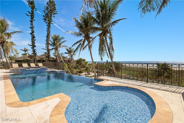 view of pool with an in ground hot tub, a water view, and a patio area