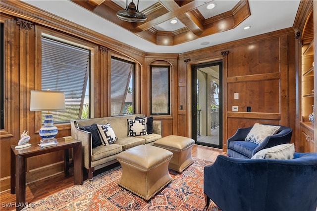 sitting room with beam ceiling, coffered ceiling, ornamental molding, wooden walls, and light wood-type flooring