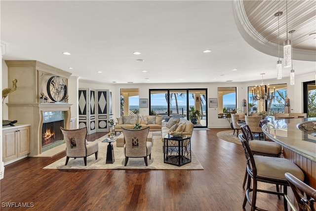 living room featuring an inviting chandelier, wood-type flooring, ornamental molding, and a premium fireplace