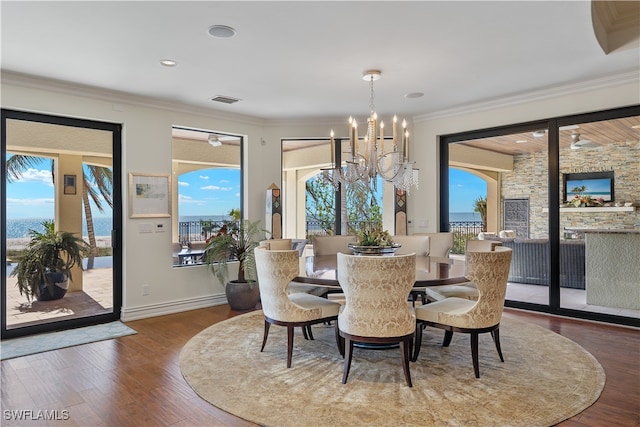 dining space featuring a wealth of natural light, crown molding, wood-type flooring, and an inviting chandelier