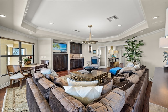 living room with a raised ceiling, ornamental molding, and dark wood-type flooring