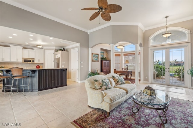 living room with french doors, ceiling fan, ornamental molding, light tile patterned flooring, and decorative columns