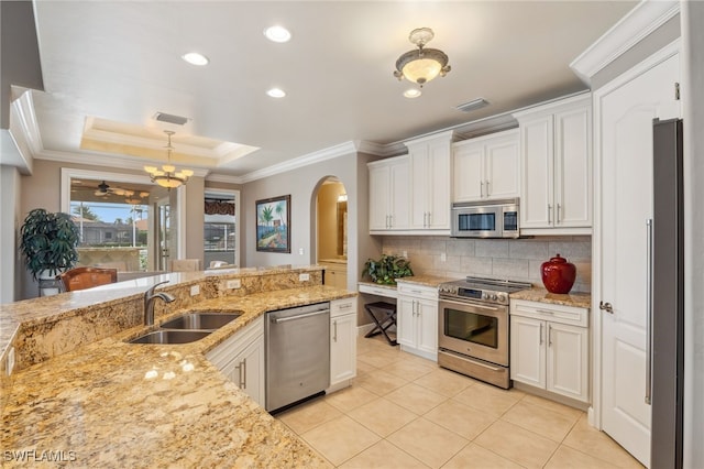 kitchen featuring white cabinetry, sink, light stone counters, decorative light fixtures, and appliances with stainless steel finishes