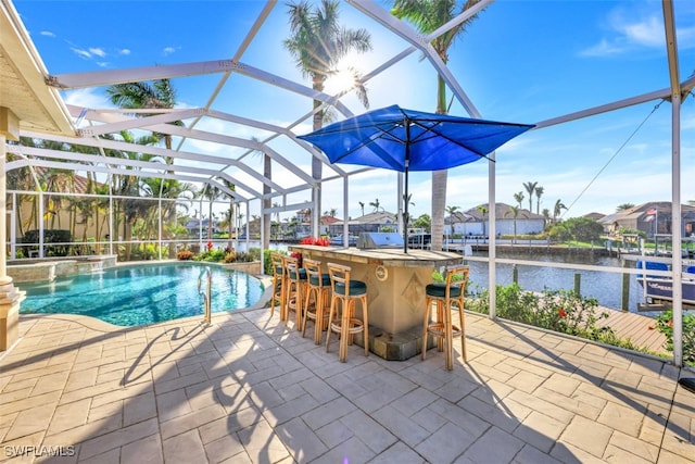 view of swimming pool with a lanai, a water view, a bar, and a patio