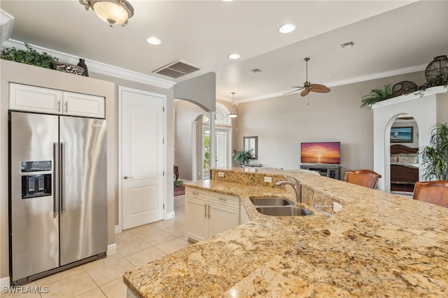 kitchen with high end refrigerator, light stone counters, ceiling fan, crown molding, and sink