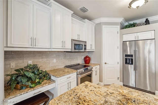 kitchen featuring appliances with stainless steel finishes, backsplash, white cabinetry, and light stone counters