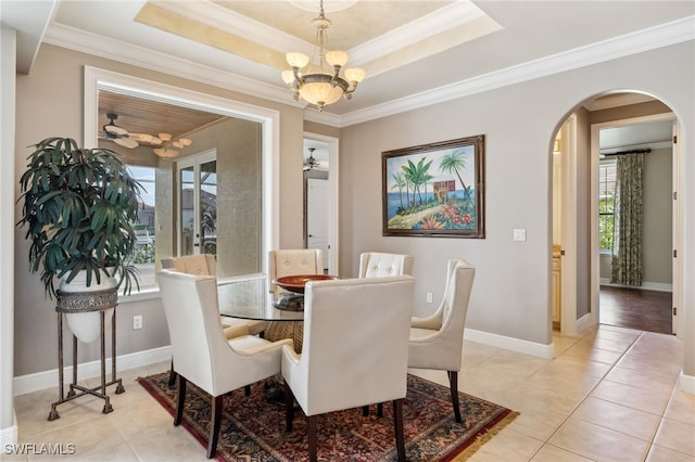 tiled dining space with a tray ceiling, crown molding, and ceiling fan with notable chandelier