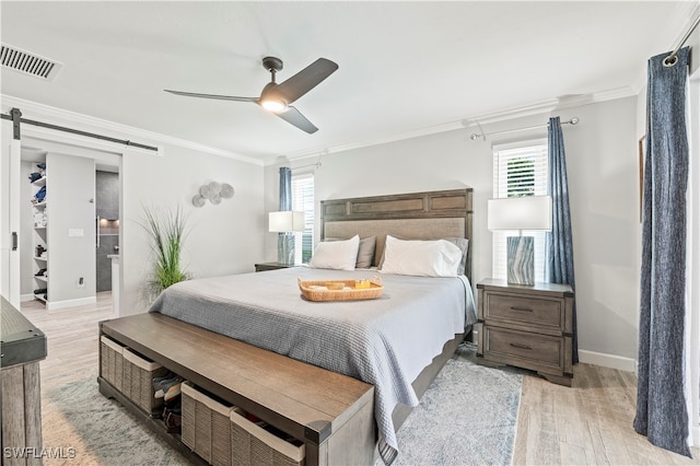 bedroom with multiple windows, ceiling fan, light hardwood / wood-style flooring, and a barn door