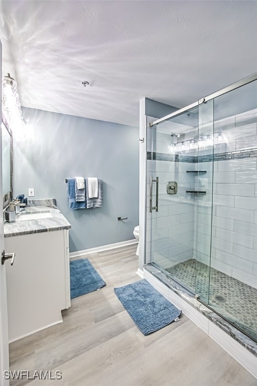 bathroom featuring vanity, hardwood / wood-style flooring, toilet, and an enclosed shower