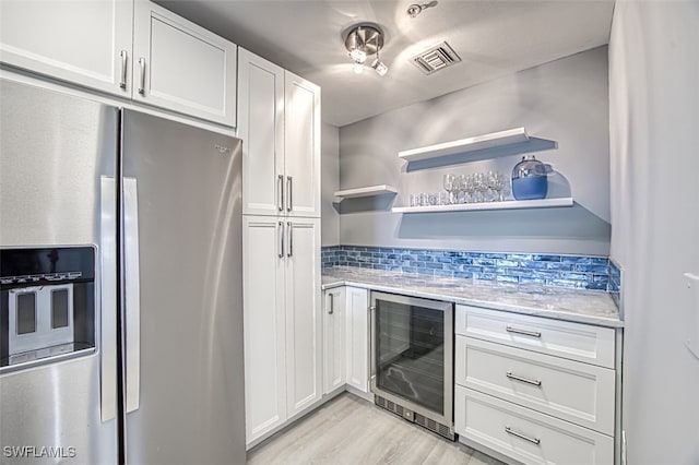 kitchen featuring wine cooler, stainless steel fridge, white cabinets, and light wood-type flooring