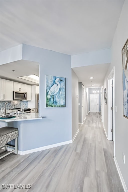 hallway with light hardwood / wood-style flooring and sink