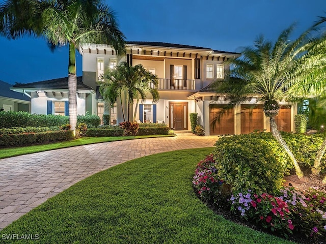 mediterranean / spanish-style house featuring a garage, a balcony, and a front yard