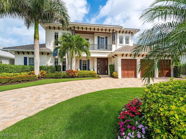 view of front facade featuring a garage, a balcony, and a front lawn