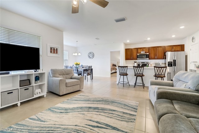 tiled living room featuring ceiling fan with notable chandelier